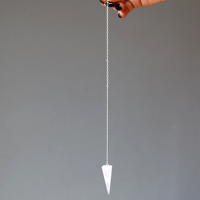 hand holding rose quartz pendulum