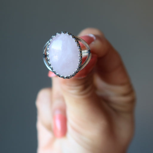hand holding pink rose quartz oval in sterling silver adjustable ring