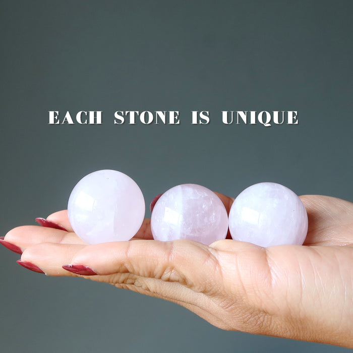three rose quartz spheres in hand