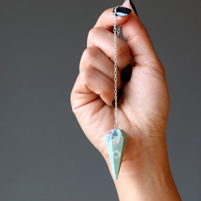 hand holding ruby fuchsite pendulum on sterling silver chain