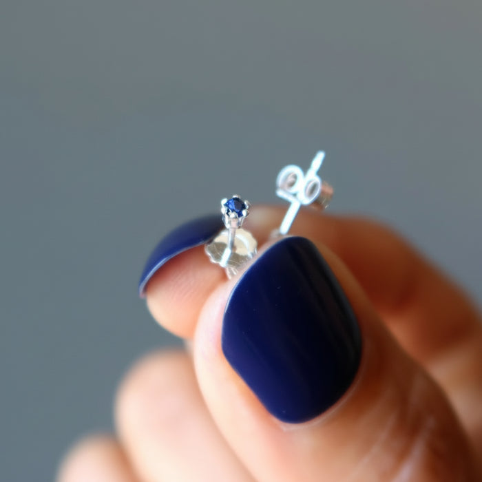 hand holding blue sapphire stud earrings