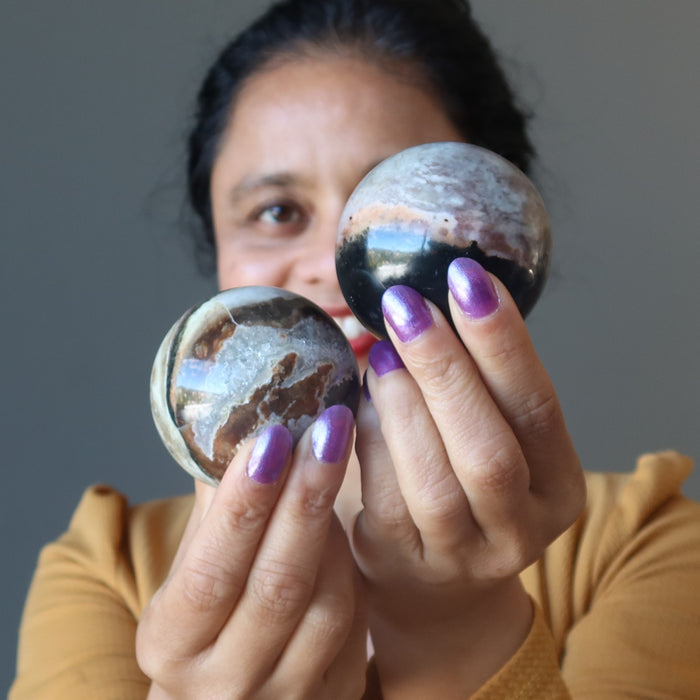 woman holding two sardonyx crystal balls
