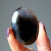 hand holding a black and brown sardonyx oval stone