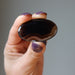 hand holding a black and brown sardonyx oval polished stone