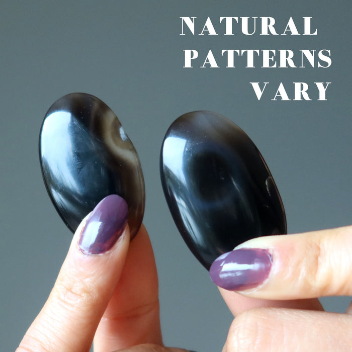 pair of black and brown sardonyx oval stones showing natural patterns vary