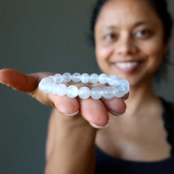 sheila of satin crystals holding forward a white selenite beaded bracelet