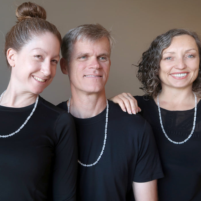two women and one man wearing white selenite necklaces