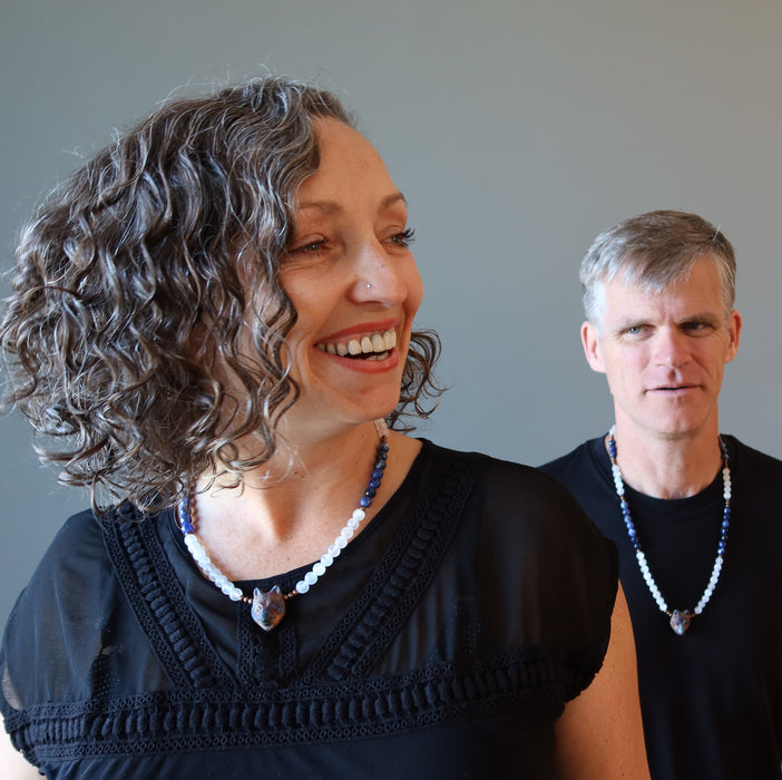man and woman both wearing selenite sodalite wolf necklaces