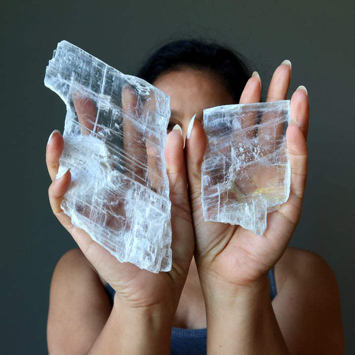 woman holding two true selenite crystals