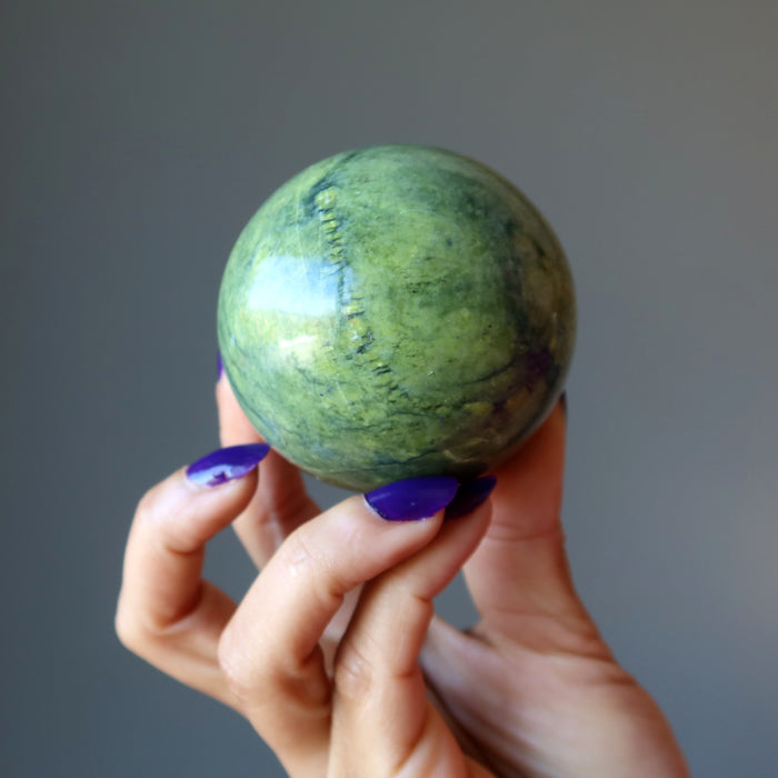 hand holding up a serpentine sphere