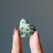 fingers holding one Serpentine Tumbled Stone