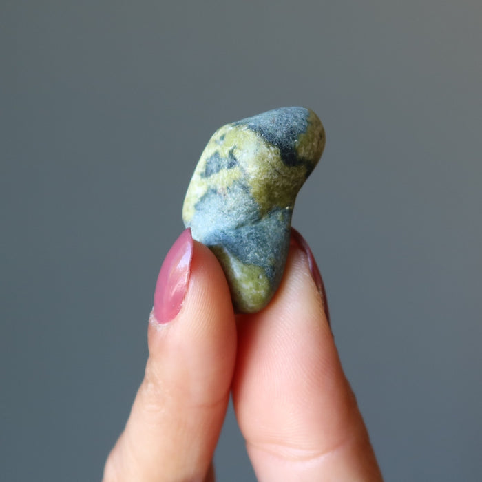 fingers holding one Serpentine Tumbled Stone