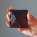 hand holding black shungite stone pyramid showing natural veins