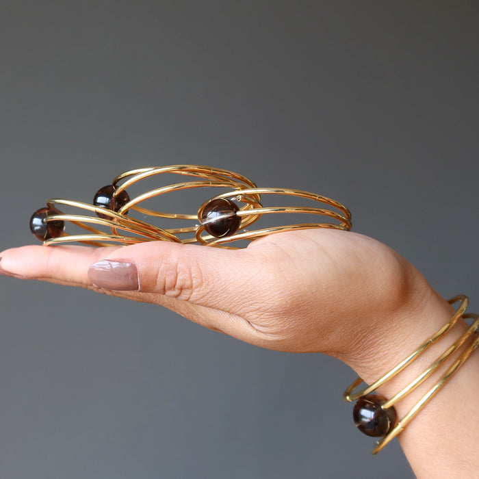 displaying 3 Smoky Quartz Bracelets on the palm and wearing one on the wrist