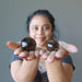 woman holding two rainbow smoky quartz spheres
