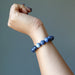 model raising hand wearing faceted round beaded sodalite bracelet on wrist