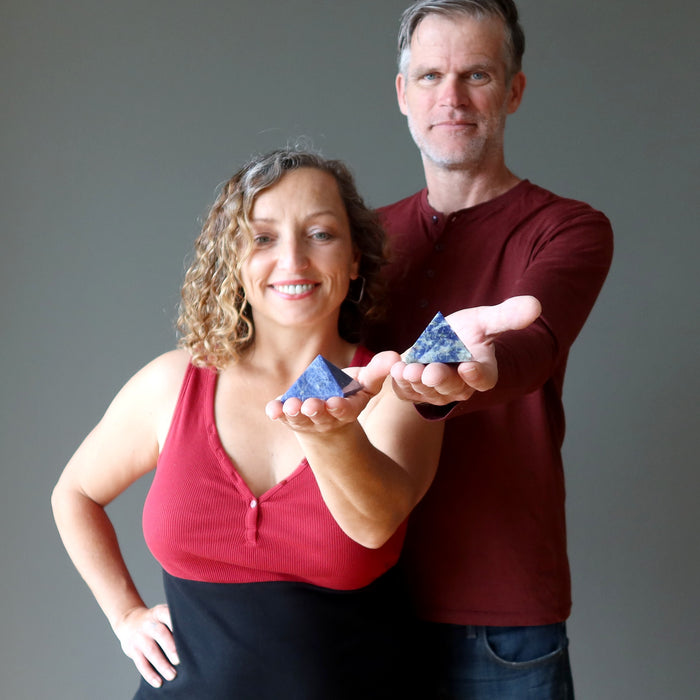 man and woman holding sodalite pyramids