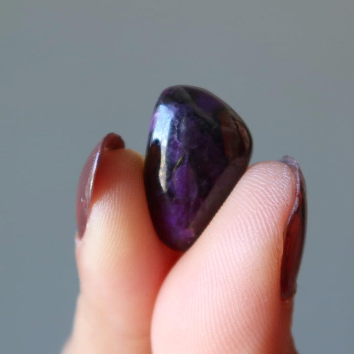 fingers holding Sugilite Polished Stone