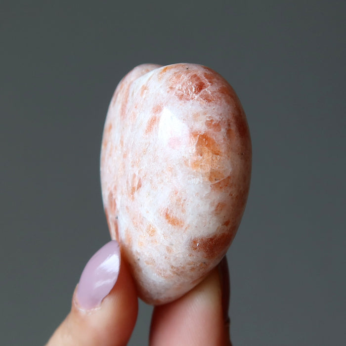 finger tips holding Sunstone Heart 