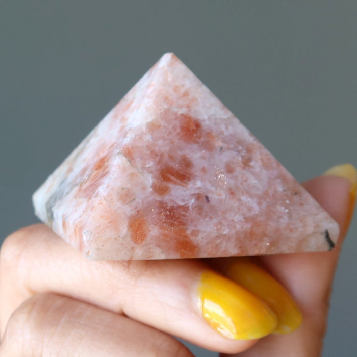 hand holding sunstone pyramid