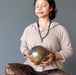 sheila of satin crystals meditating with a giant brown tigers eye sphere with veins of black hematite