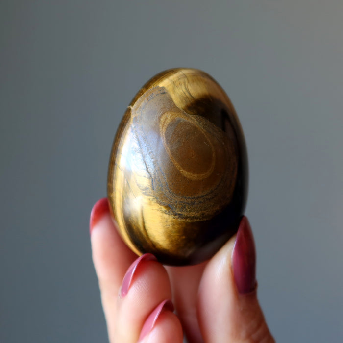 finger tips holding up Tigers Eye Egg