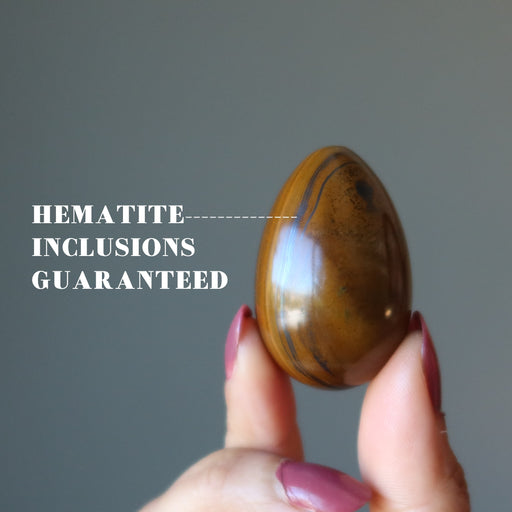 finger tips holding Tigers Eye Egg