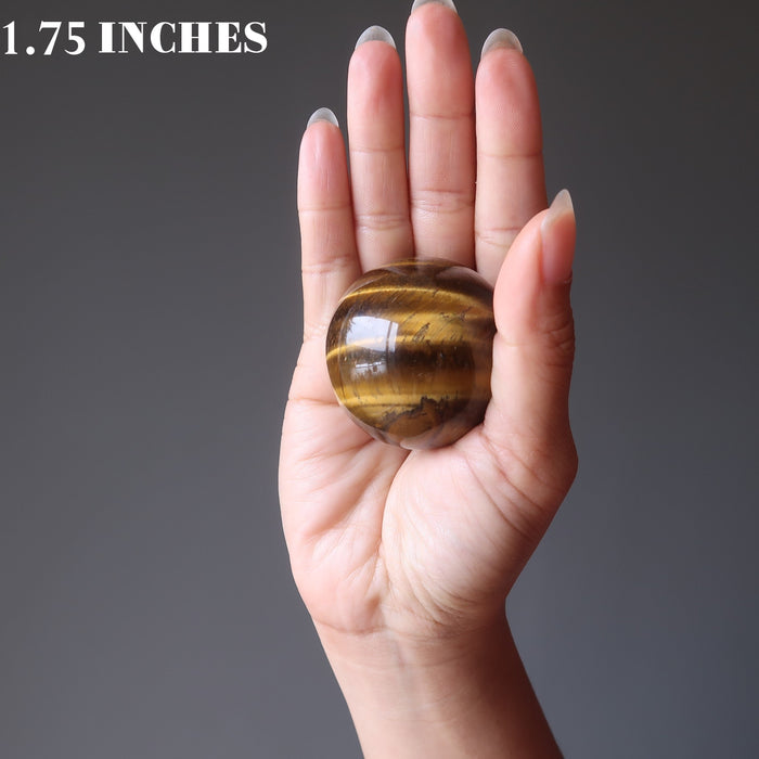 hand holding tigers eye sphere