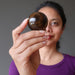 female model holding up golden tigers eye sphere