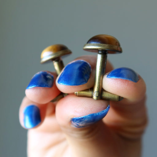 hand holding golden brown tigers eye in antique bronze cufflinks