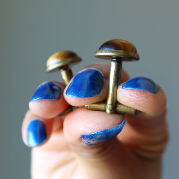 hand holding golden brown tigers eye in antique bronze cufflinks