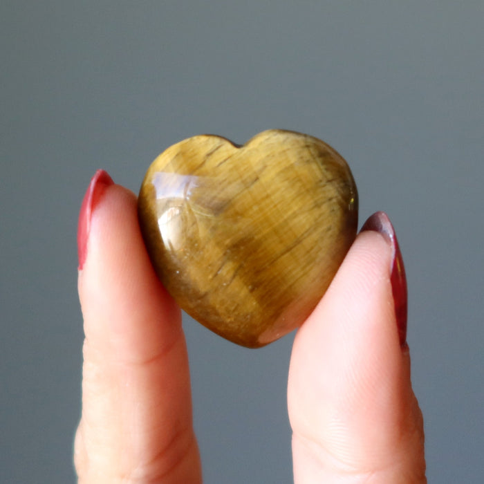 hand holding golden tigers eye heart