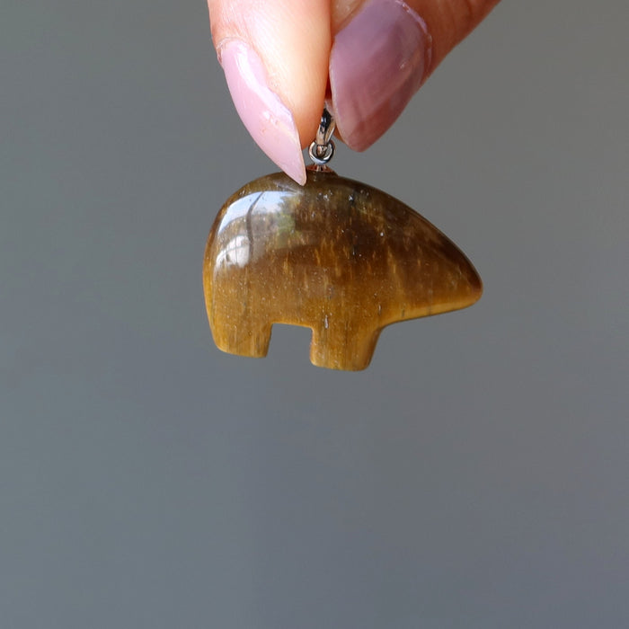 hand holding golden brown tigers eye bear fetish pendant