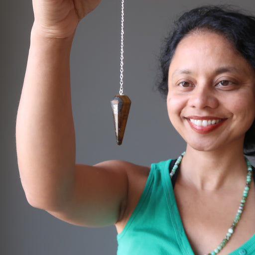 sheila of satin crystals gazing at a tigers eye pendulum