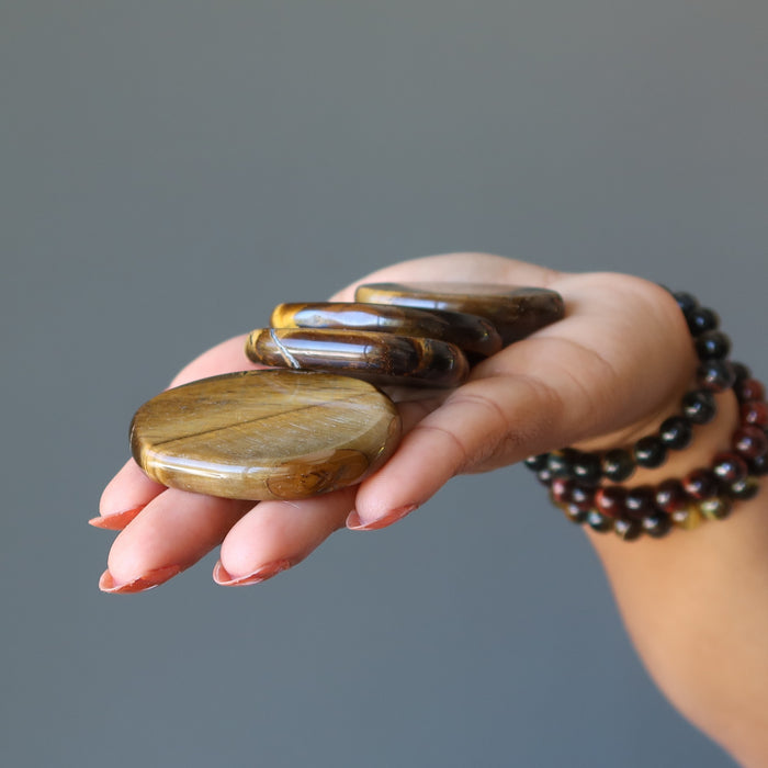 holding 4 tigers eye slabs on the palm
