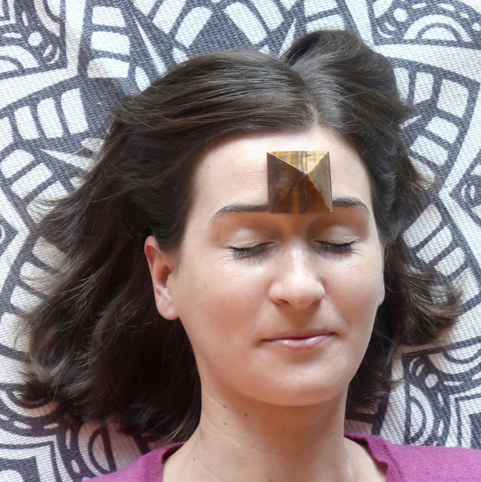 Tigers Eye Pyramid placed on woman's third eye 