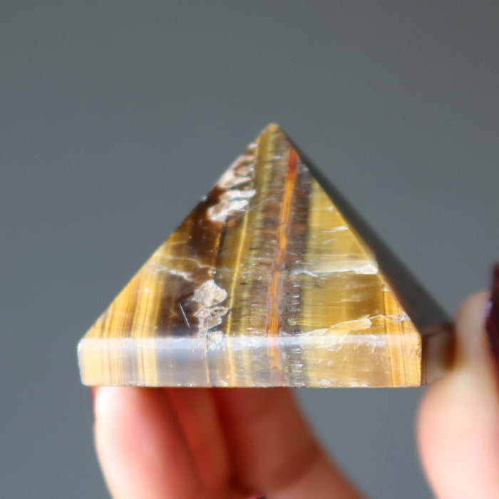 hand holding Tigers Eye Pyramid 