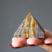 hand holding Tigers Eye Pyramid 