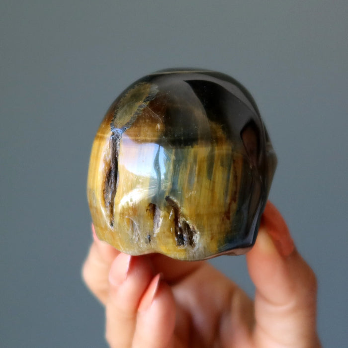hand holding a brown tigers eye skull showing the back
