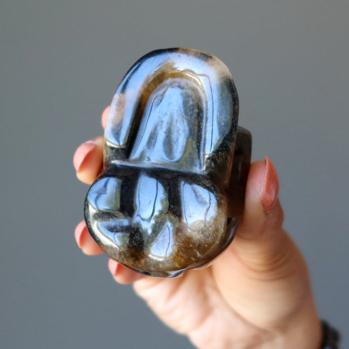 hand holding a brown tigers eye skull bottom view