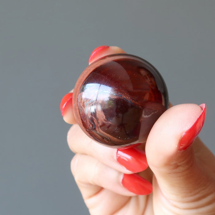 hand holding red tigers eye sphere