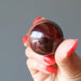 hand holding red tigers eye sphere