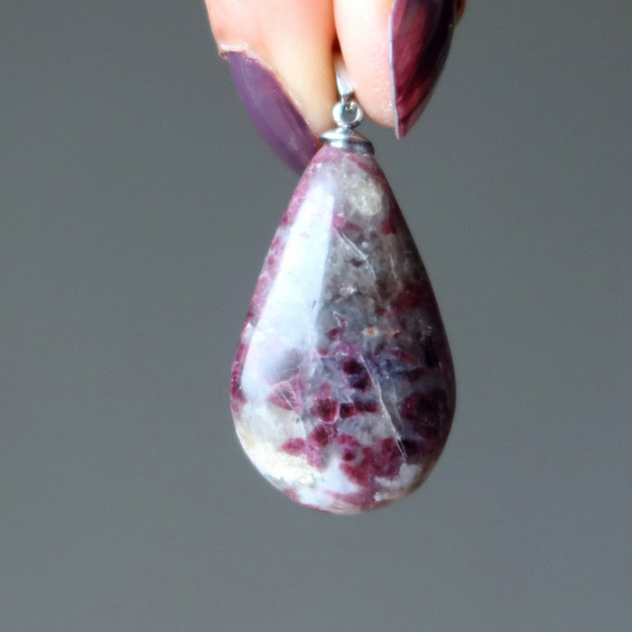 hands holding pink tourmaline pendant