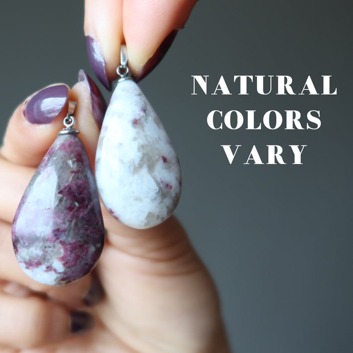 hands holding pink tourmaline pendants to show natural colors vary