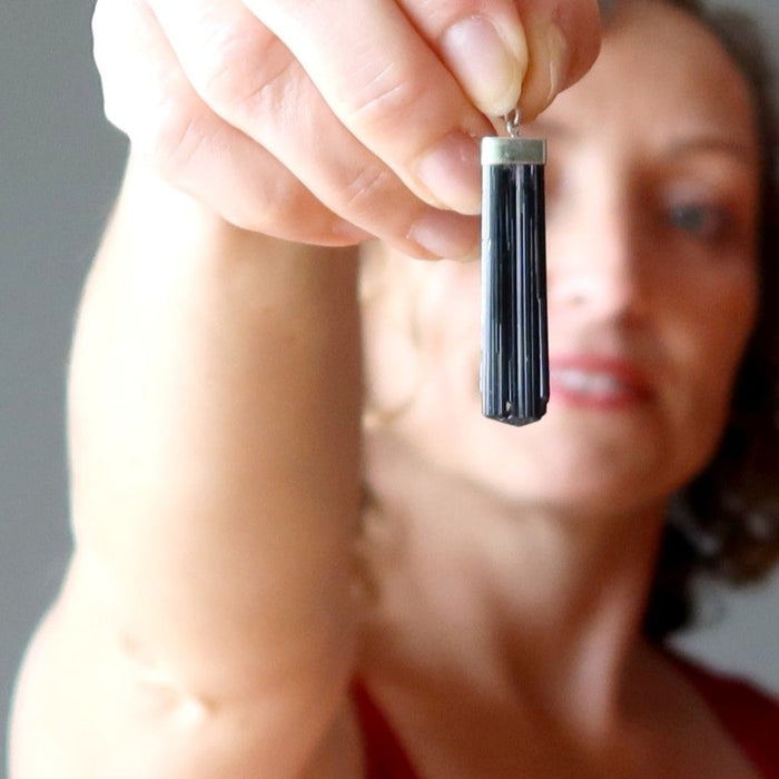 female and male models holding Raw Black Tourmaline Pendant on right hands