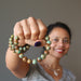 sheila of satin crystals wearing and holding green and brown turquoise jasper round beaded stretch bracelets