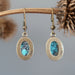back of a pair of Blue Oval Antiqued Leaf Turquoise Earrings hanging on the dry brown branch