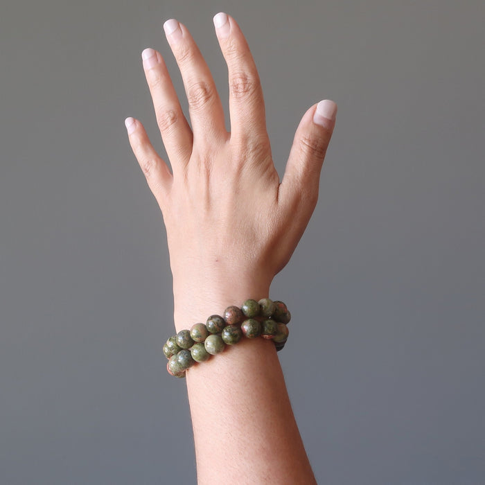 hand wearing pink and green round unakite beaded stretch bracelets