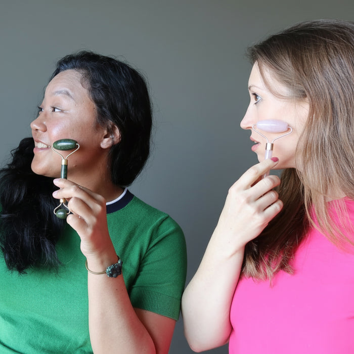 jessica of satin crystals using a jade roller on her cheek and holly using a rose quartz roller on hers