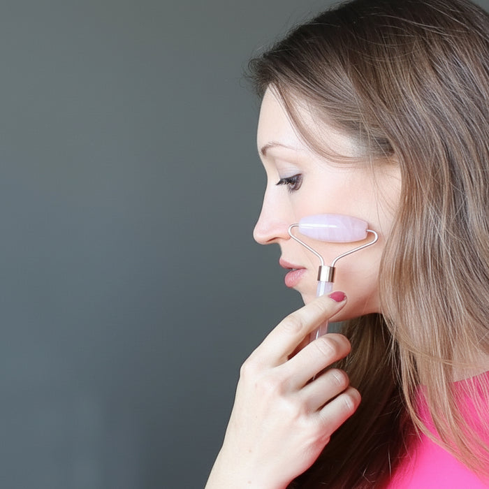 woman using A Rose Quartz facial roller wand 